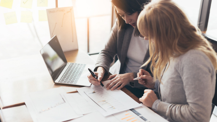 Two Women Working Through Paperwork On Their Desk